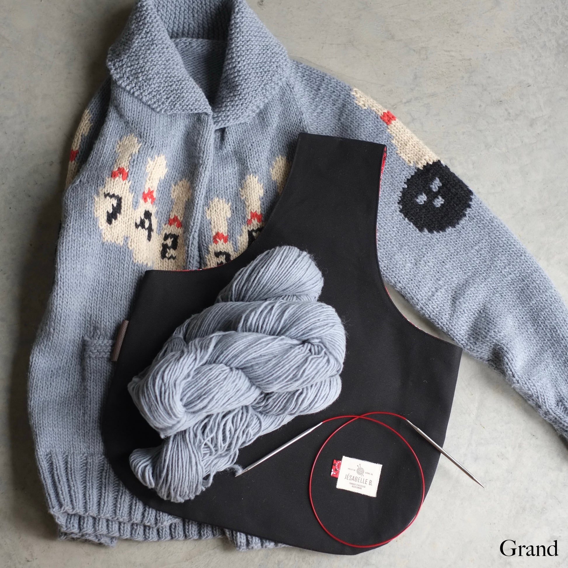 Grand sac de tricot en canvas noir sur veste Mary Maxim tricotée avec écheveaux et aiguilles — Large black canvas knitting project bag on handknit Mary Maxim vest with yarn and needles — Jésabelle B.