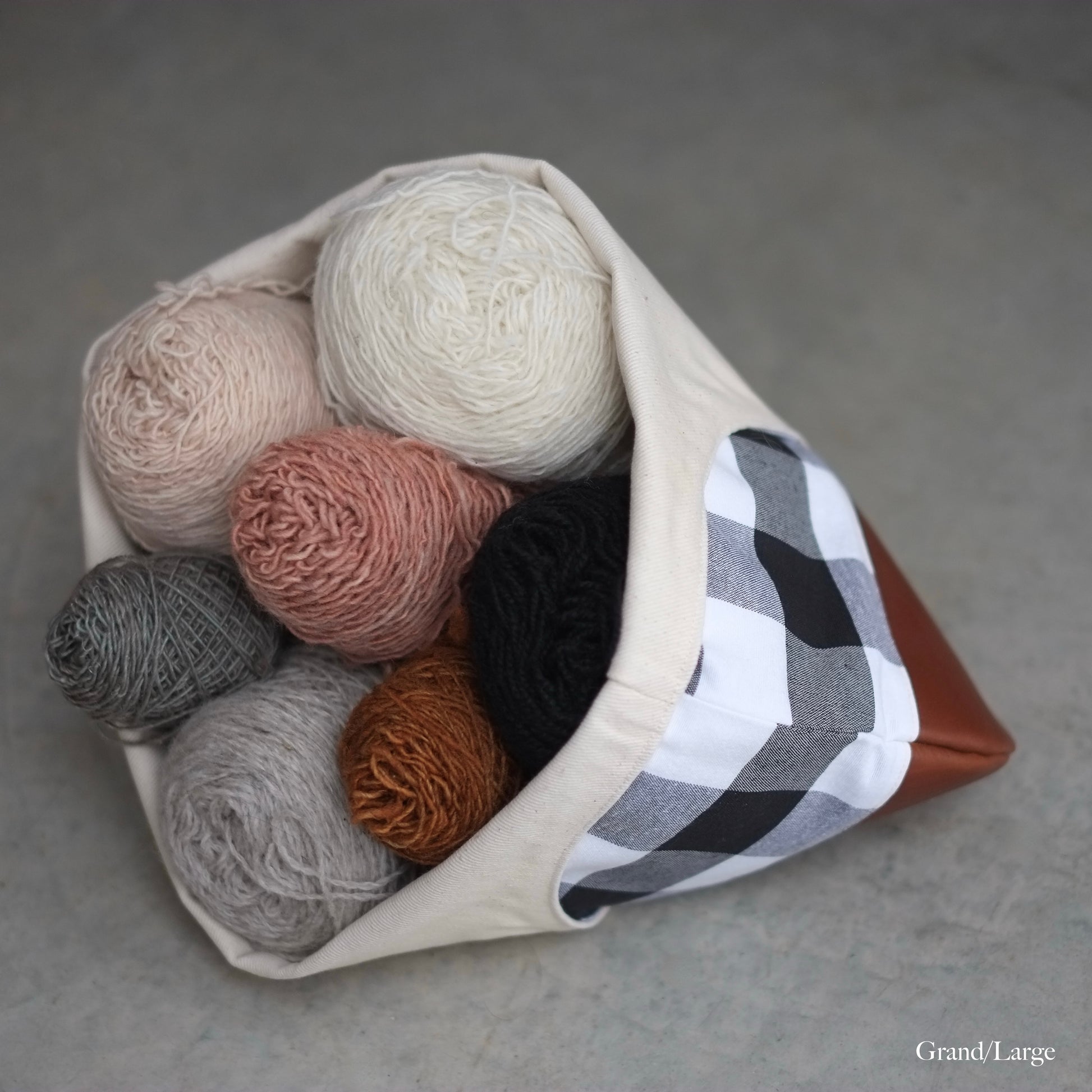 Large knitting bag full of yarn with handle under to use as a yarn basket, brown leather bottom