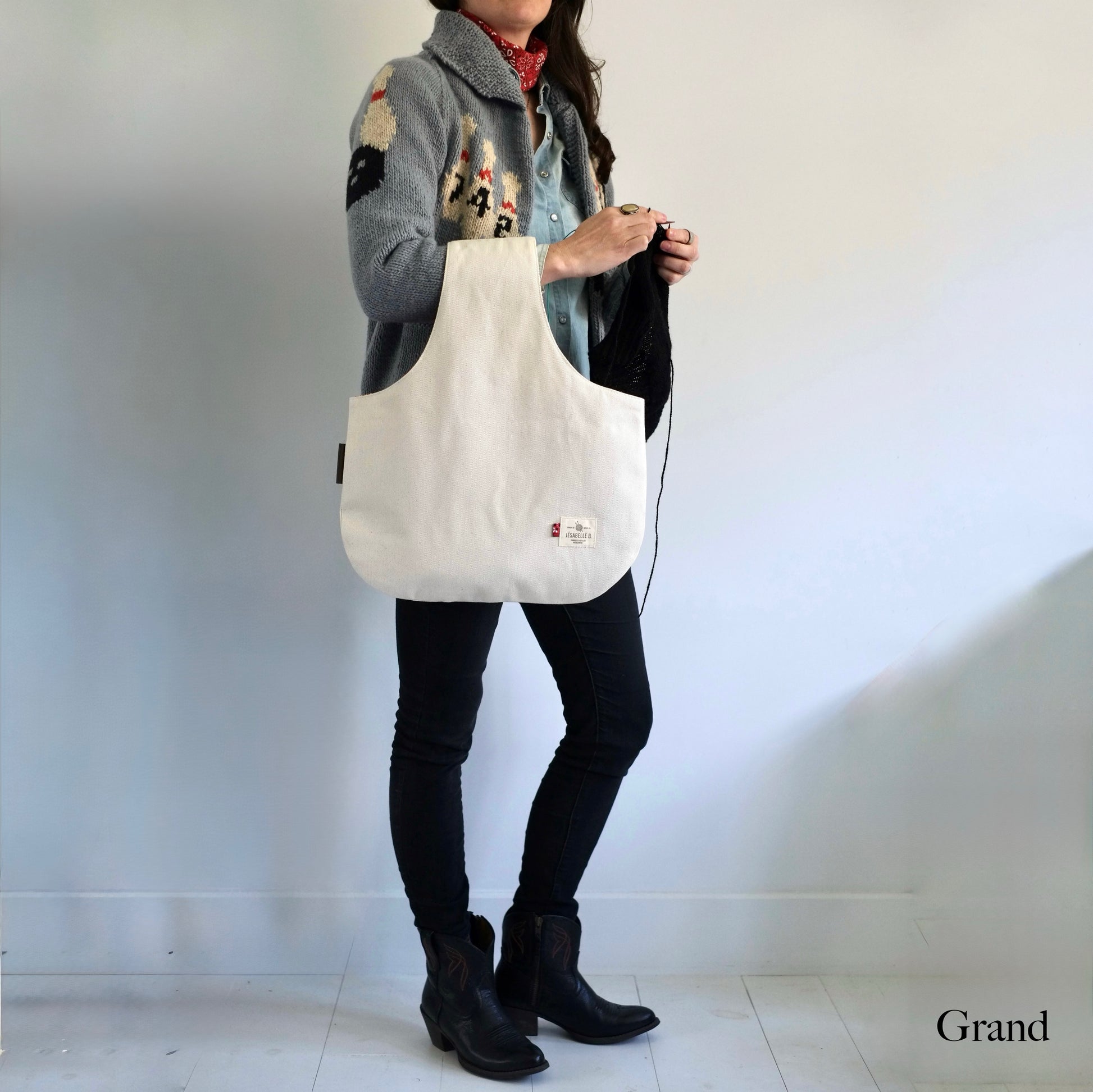 Femme debout qui tricote avec un grand sac à projet en denim beige au bras — Woman knitting with large beige denim project bag on her arm — Jésabelle B.