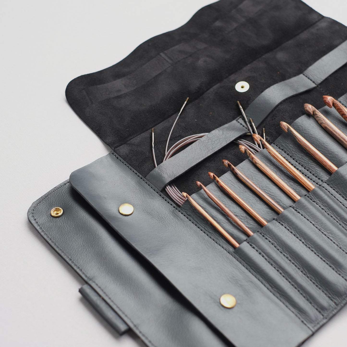 Black leather case with Tunisian crochet hooks and cables organized — minimalist design / Étui en cuir noir avec crochets tunisiens et câbles bien organisés — design minimaliste