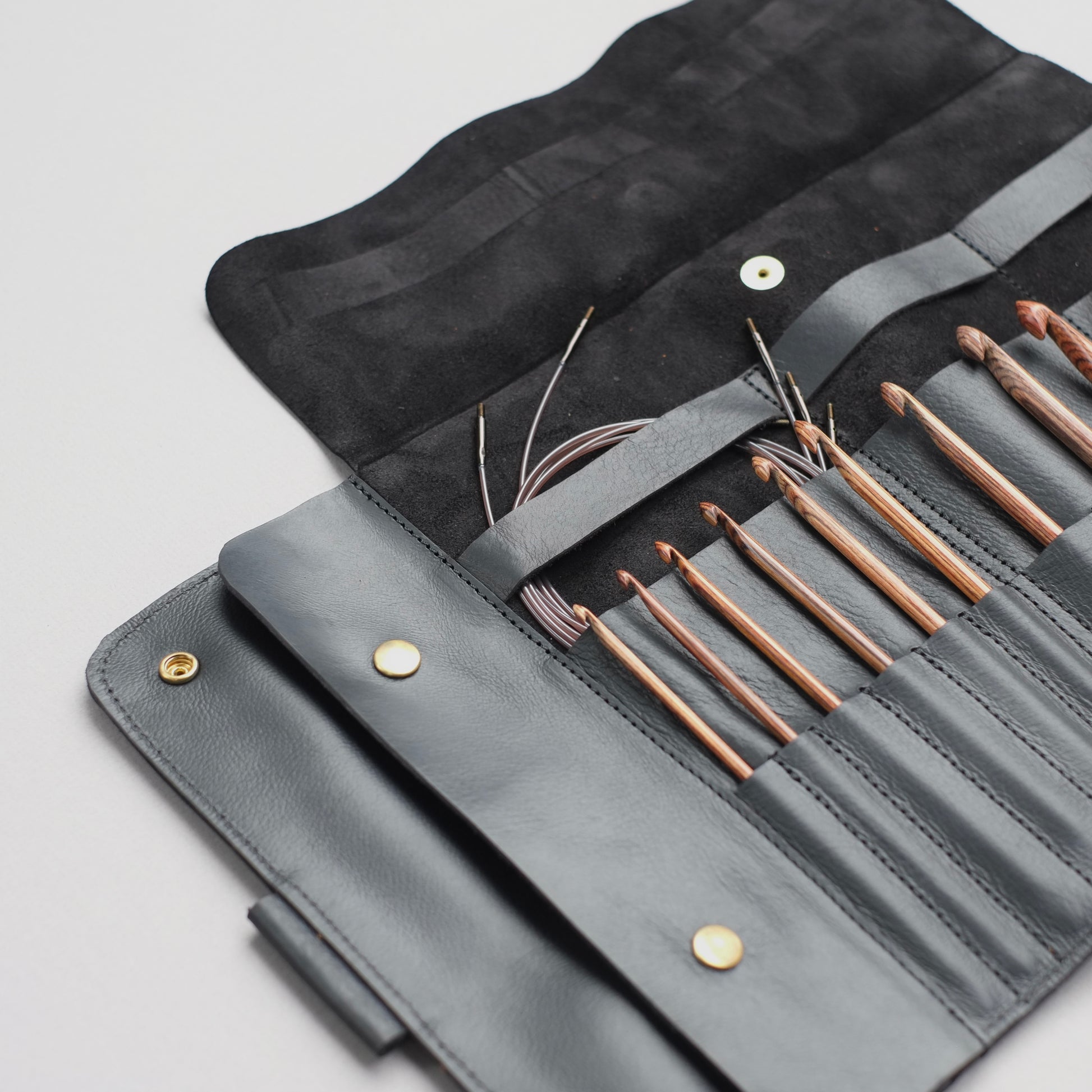 Black leather case with Tunisian crochet hooks and cables organized — minimalist design / Étui en cuir noir avec crochets tunisiens et câbles bien organisés — design minimaliste