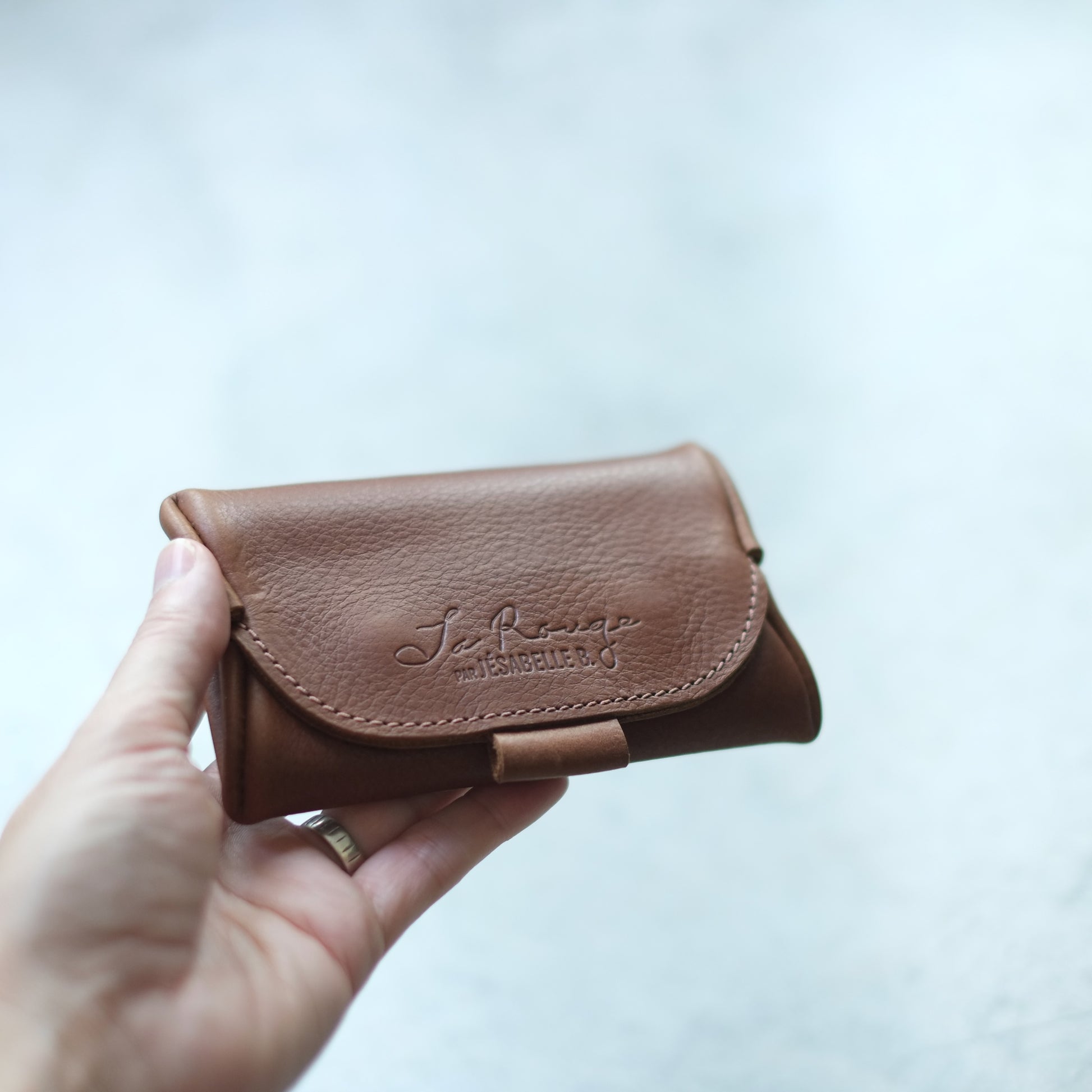 Main tenant l'étui mini de cuir brun La Rouge | Hand holding La Rouge brown leather mini case
