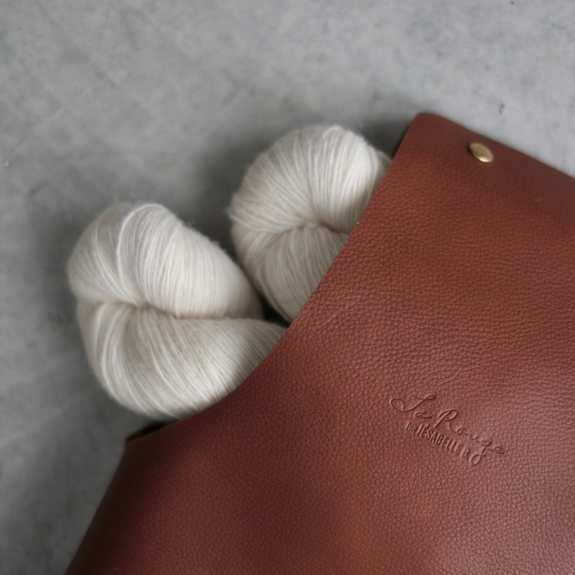 Close-up on the embossed signature and the details of the leather with some yarn inside / Gros plan sur la signature embossée dans le cuir et ses détails avec de la laine à l'intérieur du sac