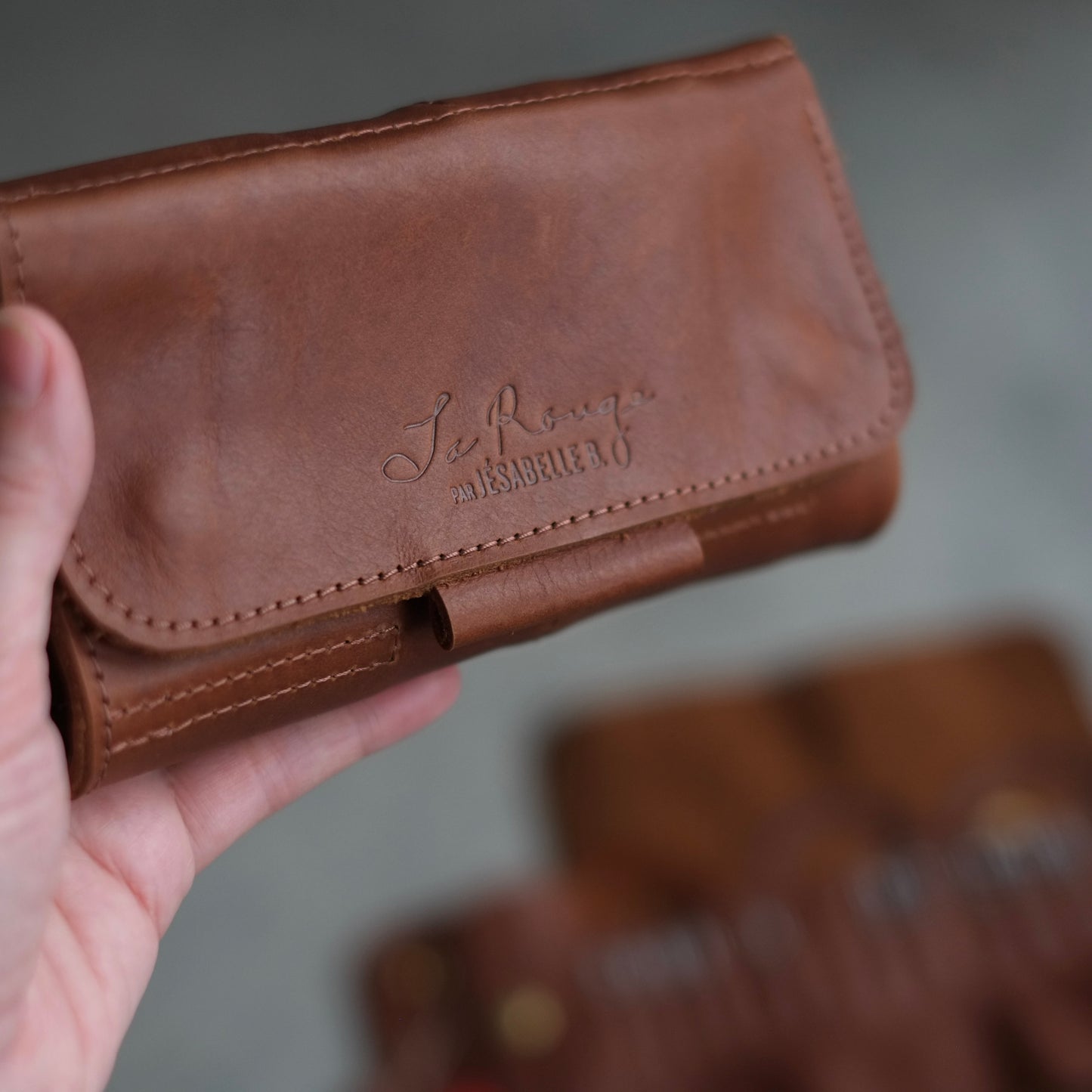 Close-up of the embossed signature and the stitching on the brown leather case / Gros plan de la signature embossée sur le cuir et de la couture parfaite sur l'étui d'aiguilles fermé.
