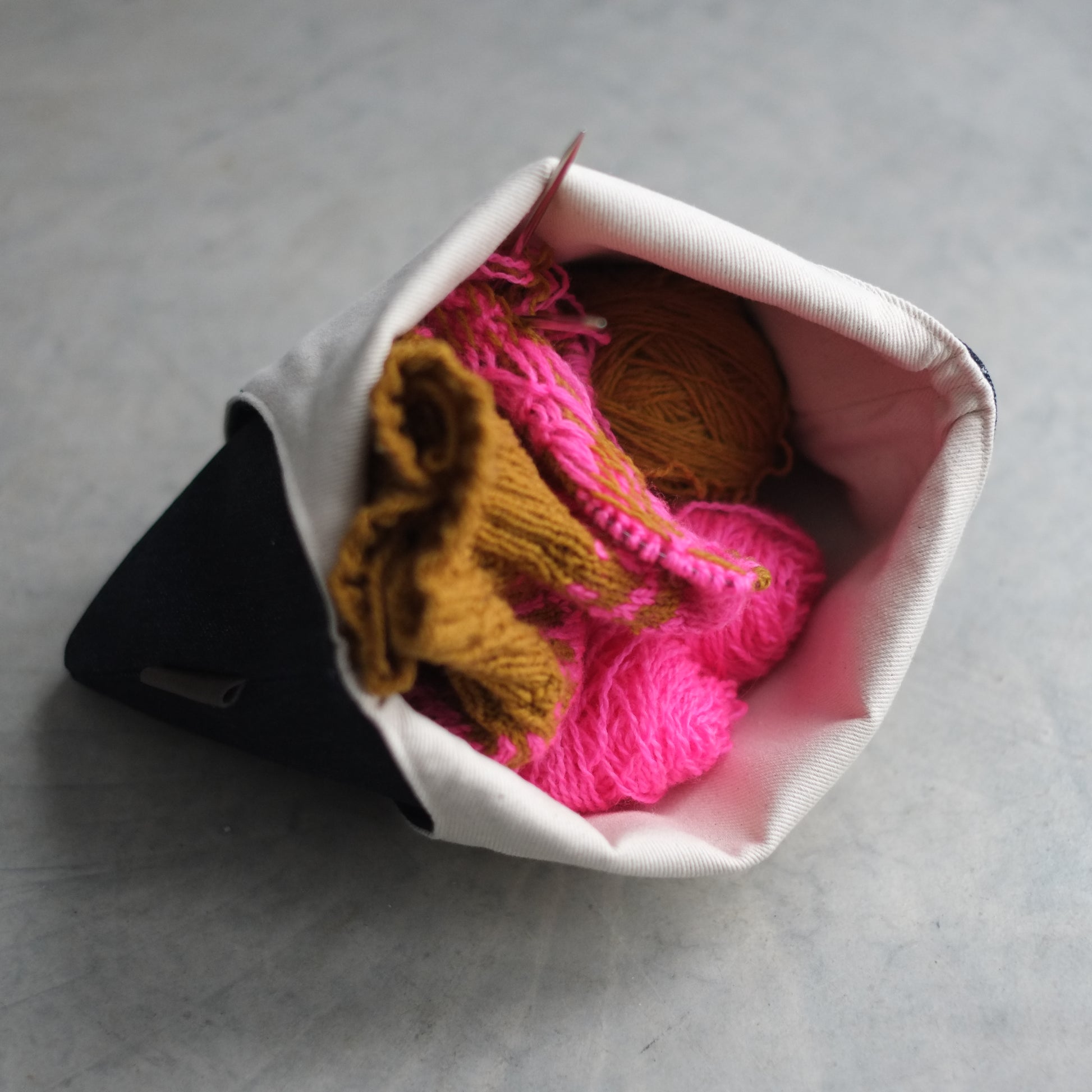 Top view of open medium knitting bag with sweater project inside — beige lining, essential knitting tool / Sac de tricot vu de haut ouvert avec projet chandail à l'intérieur — doublure beige, outil essentiel tricot