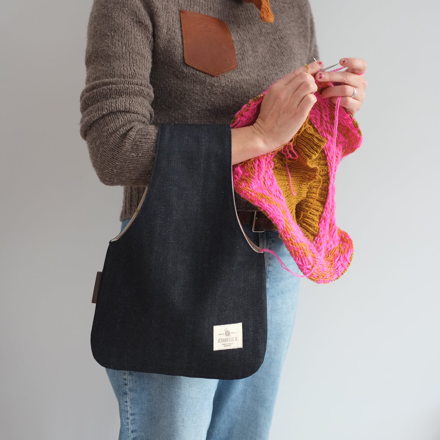 Knitter standing with medium navy denim knitting bag on wrist — portable and hands-free / Sac à laine en denim bleu marin classique au bras d'une tricoteuse debout — portatif et mains libres