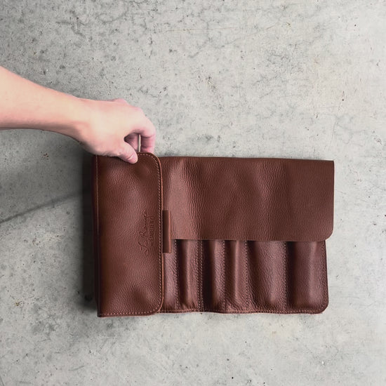 Une main pour montrer l'étui de cuir brun avec des crochets à l'intérieur