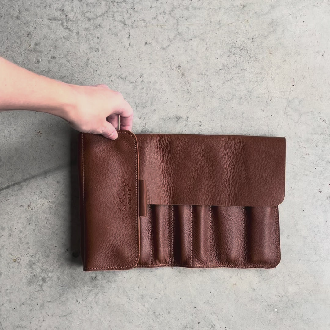 Une main pour montrer l'étui de cuir brun avec des crochets à l'intérieur
