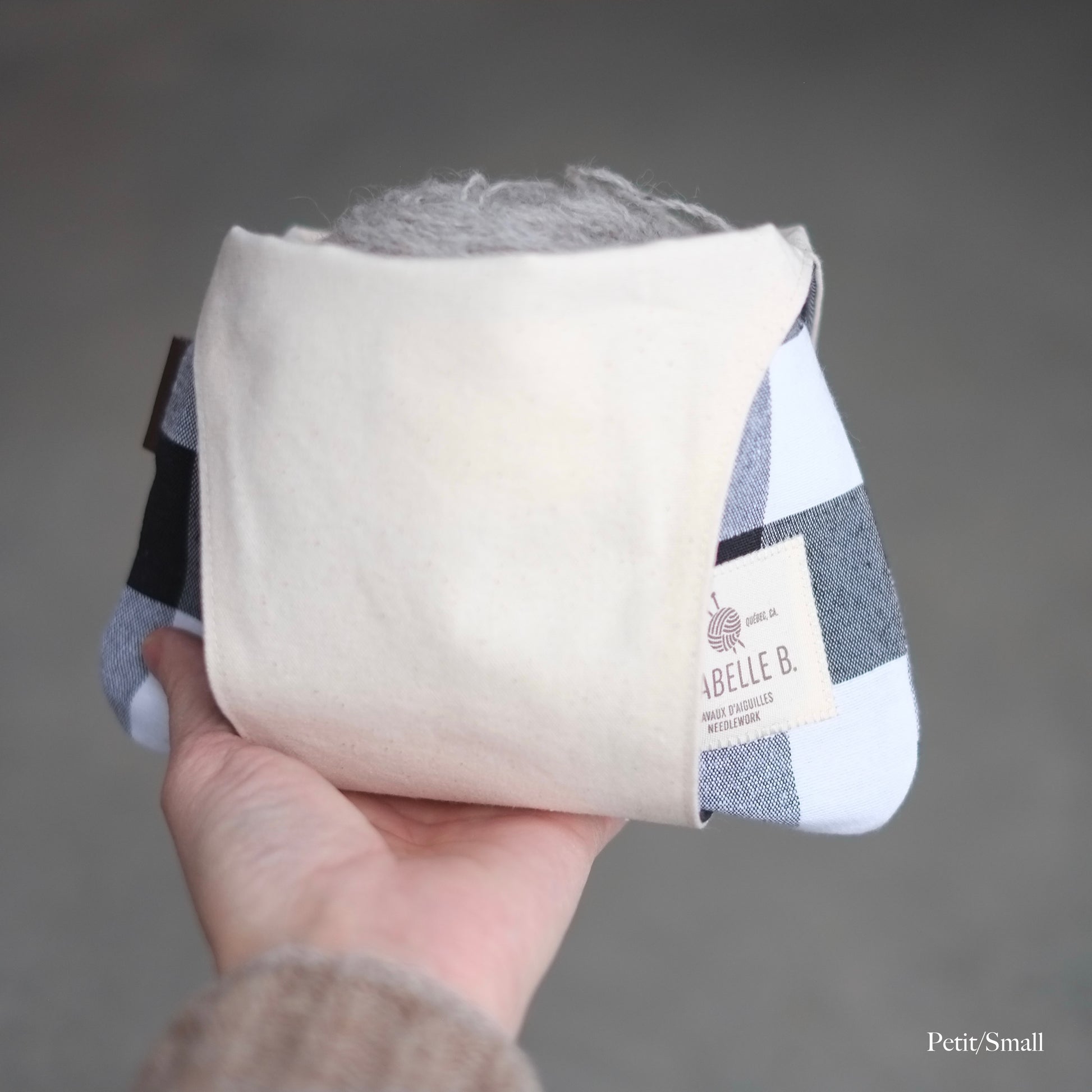 Small bag standing in a single hand that the handle has been put under to use as a basket of yarn