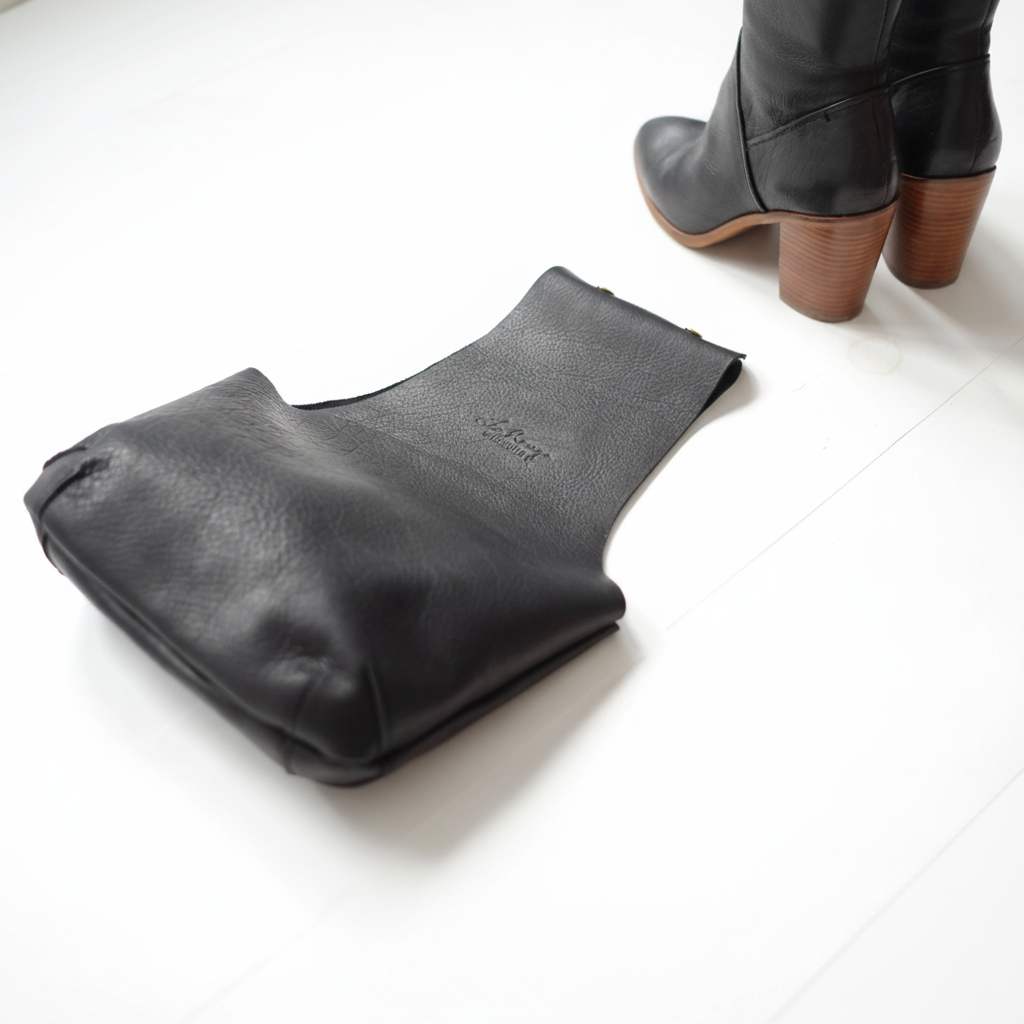 Top vue of the black leather knitting bag to see the bottom darts with some matching black leather boots / vue de haut du sac de cuir pour voir le fond avec les pinces à côté d'un paire de bottes de cuir coordonnées