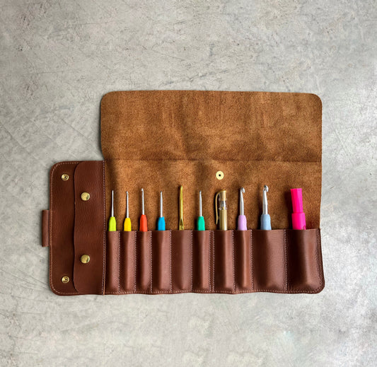Étui à crochets en cuir brun ouvert — 10 espaces du plus petit au plus grand, crochets multicolores rangés, collection La Rouge, Jésabelle B. | Brown leather crochet hook organizer open — 10 slots from smallest to largest, multicolour hooks stored, La Rouge collection, Jésabelle B.
